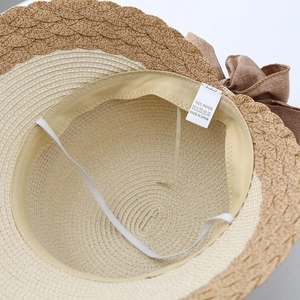 Detail view of woven straw hat interior with 100% paper label and elastic chin strap