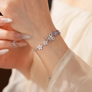 Nahaufnahme des silbernen Armbands mit Schmetterling, lila Blume und klaren Zirkonen