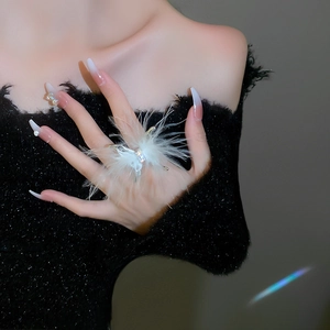 Detail of white feather butterfly ring with sparkling rhinestones worn on finger