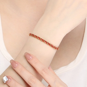 Detail of red and 18K gold braided rope bracelet worn on wrist with minimalist style