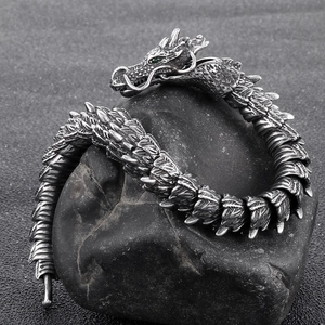 Vintage dragon bracelet in titanium steel with green eyes on a natural stone background