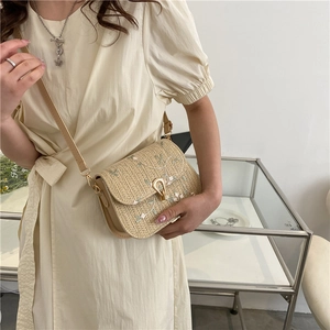 Beige straw saddle bag with delicate floral embroidery and gold metal clasp