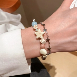 Detail of layered ceramic bead bracelet and silver star chain on a model wrist