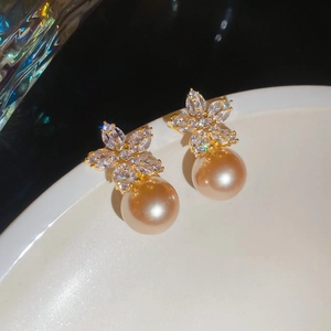 Close-up of elegant gold flower earrings with zircon petals and champagne pearl drops