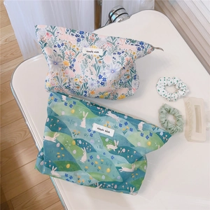 Detailed macro view of two floral cotton makeup bags with simple wish labels and zippers