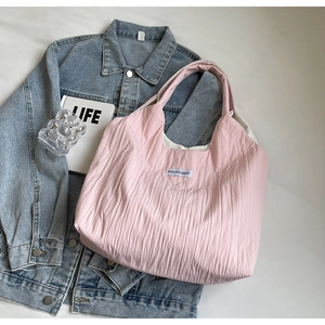 Detailaufnahme der rosa plissierten Tragetasche mit weißem Kiss Yourself Stoffetikett