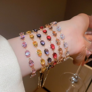 Macro shot of colorful oval zircon bracelets in pink, gold, and red layered on wrist