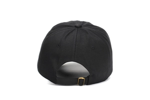 Détail de la boucle métallique réglable en bronze et texture du tissu sur la casquette noire