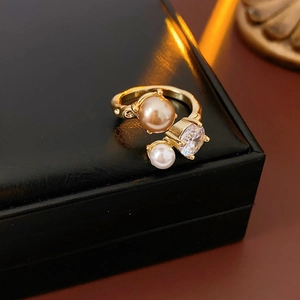 Détail d'une bague ouverte avec perle champagne et zircon sur métal doré en gros plan