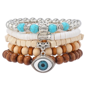 Macro shot of 5-piece stacked wooden beads and turquoise bracelet with claw and eye charms