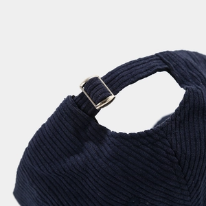 Detail of navy corduroy baseball cap showing the adjustable metal buckle and ribbed texture