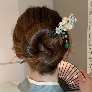 Detail of butterfly and flower hair stick with green tassel on elegant bun