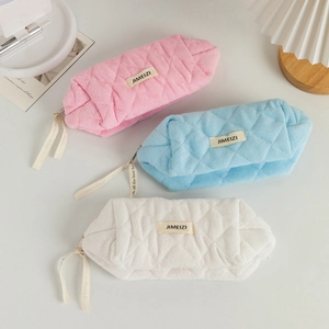 Three-piece set of quilted makeup bags in pink, blue, and white with soft textures