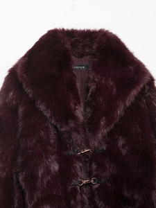 Dettaglio del cappotto in ecopelliccia bordeaux con texture morbida e ganci metallici