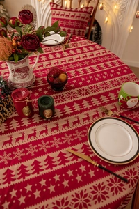 Close-up of red Christmas tablecloth with reindeer pattern and golden lace on a table