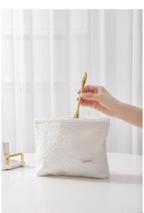 Close-up of white embossed texture canvas makeup bag with H&R BAG label and beauty tool