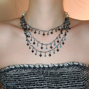 Detail of layered necklace featuring white pearls, blue crystals and heart pendants