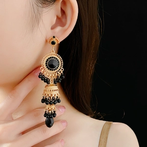 Detail of vintage gold drop earrings with black crystals and tassels on model