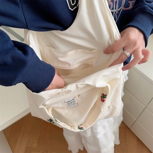Close-up of the interior structure with pockets and flower embroidery on the beige tote bag