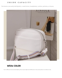 Detailed view of white pebble grain PU leather crossbody bag with striped webbing strap
