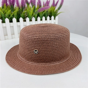 Detailed texture of brown straw boater hat with a metallic gold-tone letter M emblem