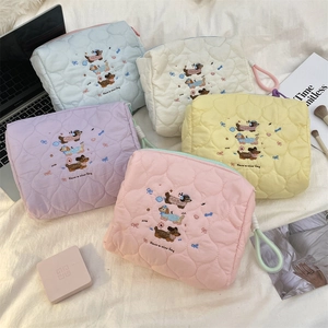 Detailed close-up of quilted heart-pattern makeup bags in five pastel colors on a bed