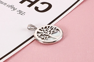 Macro shot of silver tree of life pendant with white mother of pearl inlay on pink texture