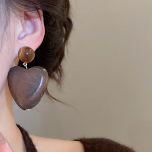 Gros plan de boucles d'oreilles cœur en bois vintage avec perle d'ambre sur un modèle