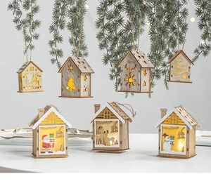 Dettaglio di una casetta di Natale in legno illuminata con motivo di renna appesa a un ramo