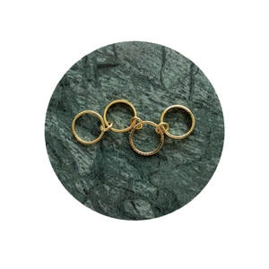 Minimalist gold plated rings set with gemstones on a green marble base stand