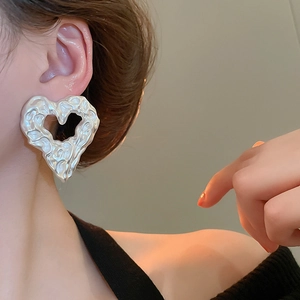 Detailed close-up of chunky silver heart earrings with irregular crumpled metal texture