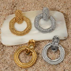 Textured chunky hoop earrings in gold and silver finish on natural stone background