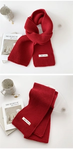 Macro detail of red chunky knit scarf texture with stylish brand label on white table