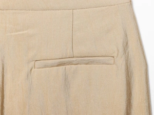 Macro-detail van de champagnegouden satijnen stof met elegante zakstiksels en zijdetextuur
