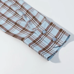 Détail du poignet d'une chemise en popeline à carreaux avec boutons et motifs bleu ciel
