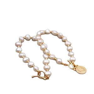 Freshwater pearl bracelet with gold toggle clasp and coin pendant on white background
