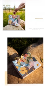 Detail of floral gift bag featuring pink and yellow patterns with golden handles