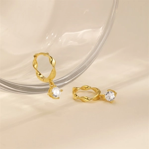 Detailed view of gold twisted earrings with a dangling clear round zirconia charm