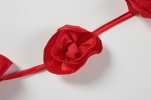 Detail of red satin 3D flower decoration with glossy finish on a slim dress strap