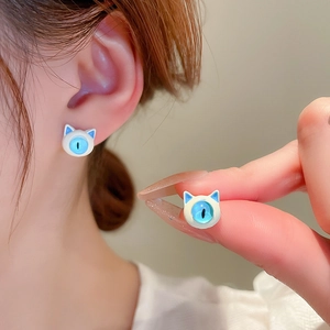 Detailed shot of cute blue and white cat-shaped stud earrings worn on the earlobe