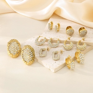 Vue détaillée de boucles d'oreilles ovales dorées avec cristaux sur pierre beige