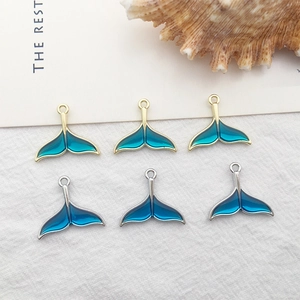 Detailed macro view of whale tail charms with blue enamel inlay and metal frames