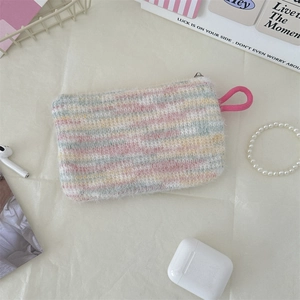 Flat lay of a plush heart lipstick makeup bag with soft colorful stripes and pink lanyard