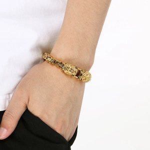 Side view of men's chunky gold-tone lion head bracelet on wrist showing braided link texture