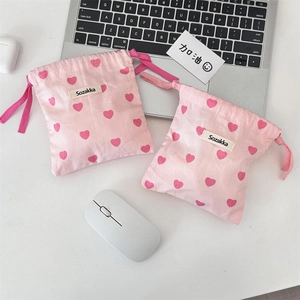 Detail of pink canvas drawstring bags with red heart patterns and brand woven label