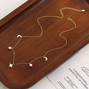 Detail of s925 silver star and moon necklace with pearls on a vintage wooden tray