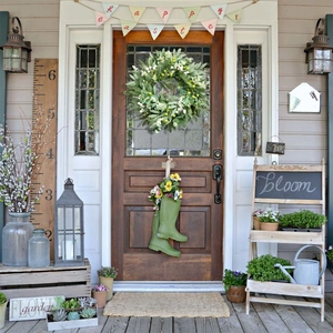 Artificial olive leaf and white berry wreath hanging on a rustic wooden front door