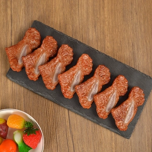 Realistic artificial grilled lamb chop food models on black stone tray with wooden background