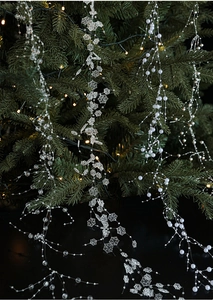 Close-up of clear snowflake ornaments and pearl bead garland on a Christmas tree