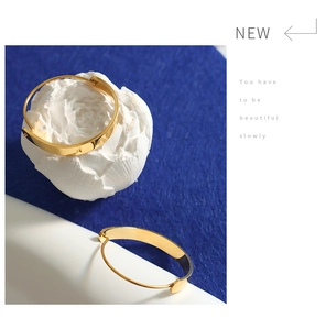 Polished gold tiered hoop earrings on white floral props against blue background
